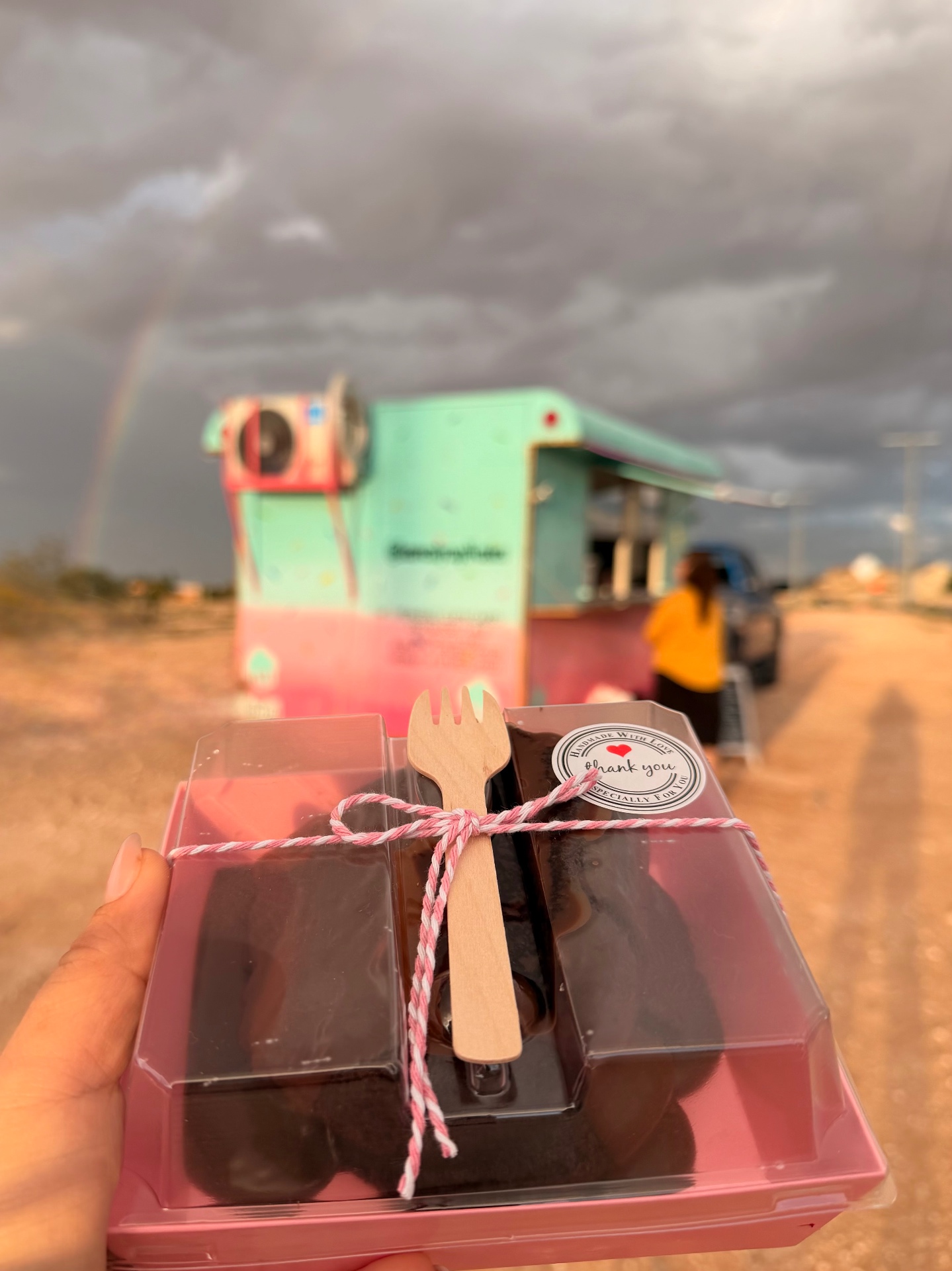 Chocolate brownie dessert box in front of the trailer with a rainbow