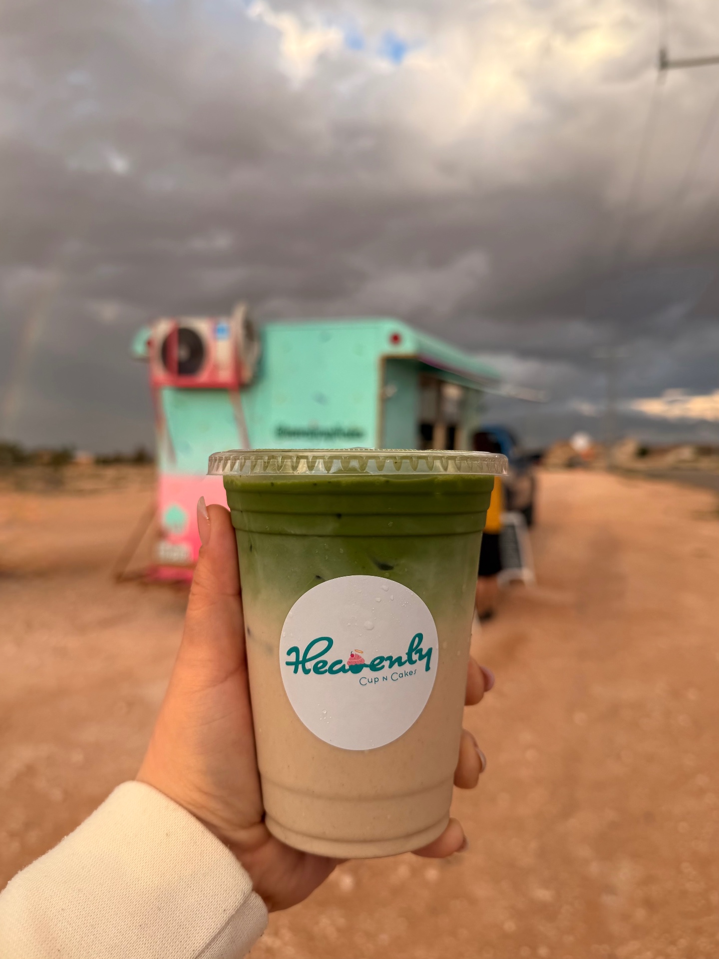 Iced matcha latte with Heavenly logo in front of the food trailer